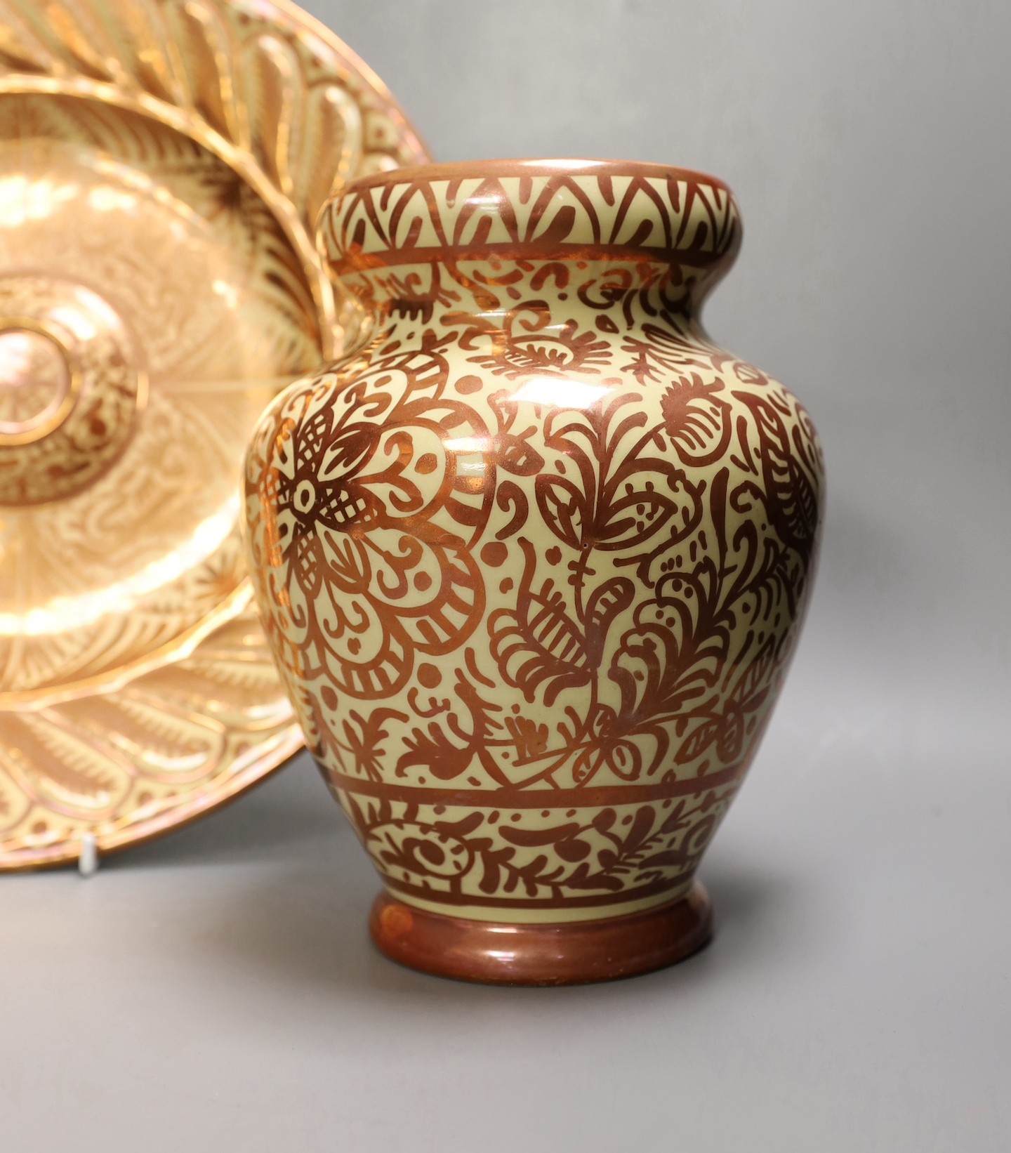 A Hispano Moresque style copper lustre pottery charger and vase, 24cm tall